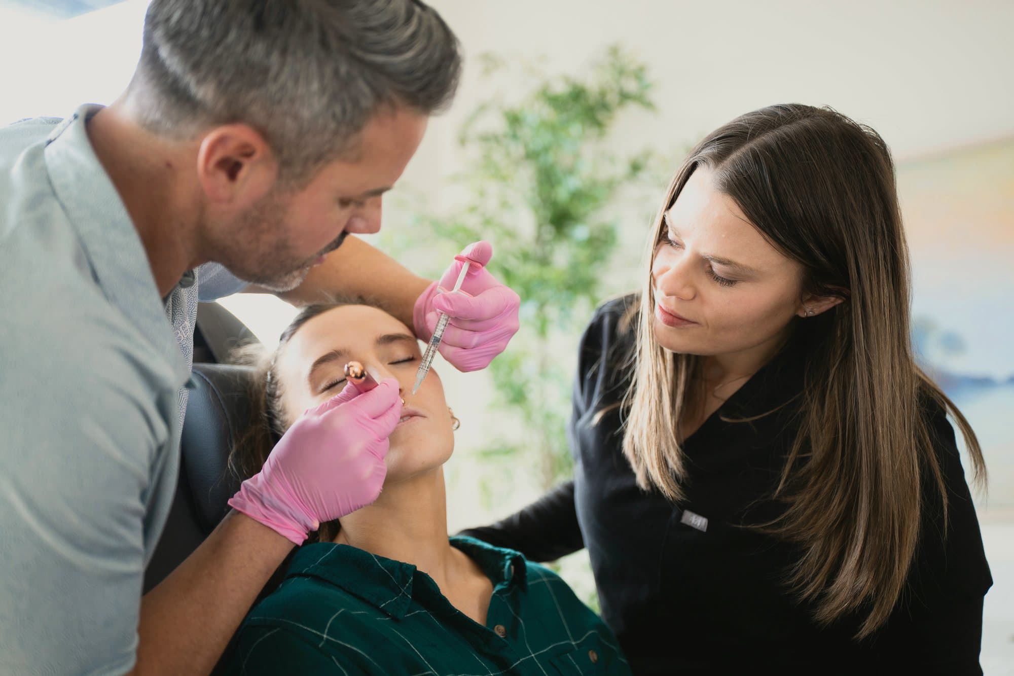 Ben Tracy, MD, treating a patient's forehead while a colleague looks on.